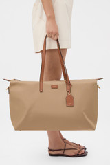 Profile view of model wearing the Oroton Lilly Nylon Weekender Tote in Mushroom/Cognac and Nylon fabric for Women .