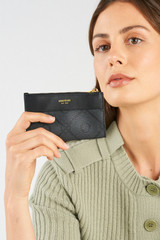 Profile view of model wearing the Oroton Harvey Signature Mini 4 Credit Card Zip Pouch in Black and Nylon canvas base cloth material with PVC coating (70% PVC, 30% polyester) for Women .