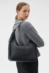 Profile view of model wearing the Oroton Dorit Hobo Bag in Black and Premium pebble leather for Women .