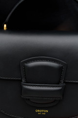 Profile view of model wearing the Oroton Carter Mini Day Bag in Black and Premium smooth leather for Women .