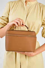 Profile view of model wearing the Oroton Eve Large Top Handle Beauty Case in Tan and Pebble leather for Women .
