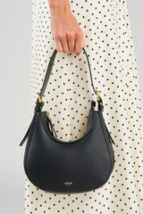 Profile view of model wearing the Oroton Dylan Mini Hobo in Black and Premium pebble leather for Women .