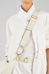 Profile view of model wearing the Oroton Heather Long Light Gold Webbing Strap in CREAM/MILK and 100% polyester material for Women .