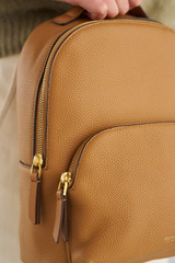 Profile view of model wearing the Oroton Dylan Small Backpack in Tan and Pebble leather for Women .