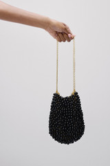 Profile view of model wearing the Oroton Vera Evening Bag in Black and Linked brass O ring chain with coated copper balls for Women .