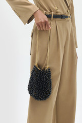 Profile view of model wearing the Oroton Vera Evening Bag in Black and Linked brass O ring chain with coated copper balls for Women .