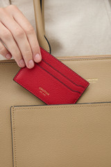 Profile view of model wearing the Oroton Iris Credit Card Sleeve in Dark Ruby and Premium pebble leather for Women .