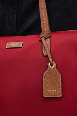 Profile view of model wearing the Oroton Lilly Nylon Light Weight Tote Bag in DARK RUBY and Nylon fabric for Women .