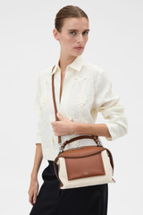 Profile view of model wearing the Oroton Mica Canvas Broguing Bowler in NATURAL/PENNY BROWN and Premium canvas material for Women .