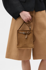 Profile view of model wearing the Oroton Margot Suede Tiny Bucket Bag in Teak and Premium suede leather for Women .