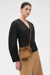 Profile view of model wearing the Oroton Margot Suede Tiny Bucket Bag in Teak and Premium suede leather for Women .