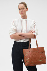 Profile view of model wearing the Oroton Polly Perforated Medium Tote in Cognac and Premium smooth leather for Women .