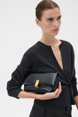 Profile view of model wearing the Oroton Etta Crackle Medium Clutch in Black and Premium crackle leather for Women .
