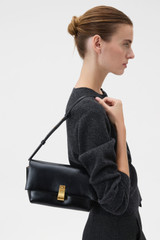 Profile view of model wearing the Oroton Etta Crackle Medium Clutch in Black and Premium crackle leather for Women .