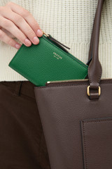 Profile view of model wearing the Oroton Eve Mini 4 Credit Card Zip Pouch in CROCODILE and Premium pebble leather for Women .