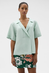 Profile view of model wearing the Oroton Short Sleeve Wrap Shirt in Glass and 100% silk dupion fabric for Women .
