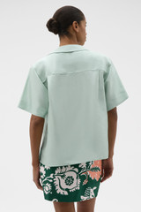 Profile view of model wearing the Oroton Short Sleeve Wrap Shirt in Glass and 100% silk dupion fabric for Women .