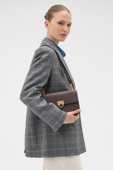 Profile view of model wearing the Oroton Yvette Medium Clutch Bag in Coffee Bean and Premium textured leather for Women .