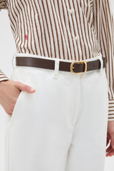 Profile view of model wearing the Oroton Inez Reversible Brass Belt in Coffee Bean/Tan and Premium saffiano leather for Women .