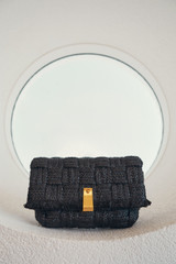 Profile view of model wearing the Oroton Etta Texture Medium Clutch in Dark Chocolate and Woven straw material for Women .
