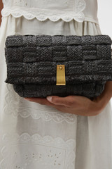 Profile view of model wearing the Oroton Etta Texture Medium Clutch in Dark Chocolate and Woven straw material for Women .