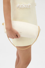 Profile view of model wearing the Oroton Naia Texture Clutch in Clotted Cream and Textured leather outer for Women .