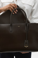 Profile view of model wearing the Oroton Muse 15" Worker Tote in Dark Chocolate and Saffiano leather exterior for Women .