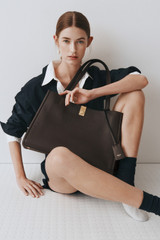 Profile view of model wearing the Oroton Mille Work Tote in Dark Chocolate and Premium pebble leather for Women .