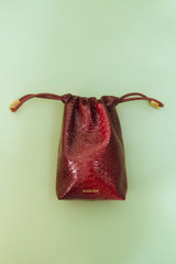 Profile view of model wearing the Oroton Nola Texture Drawstring Pouch in Copper and Premium textured leather for Women .