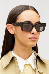 Profile view of model wearing the Oroton Spencer Sunglasses in Signature Tort and Acetate material for Women .