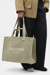 Profile view of model wearing the Oroton Everyday Tote in Pistachio and 99.9% recycled polyester material for Women .