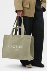 Profile view of model wearing the Oroton Everyday Tote in Pistachio and 99.9% recycled polyester material for Women .