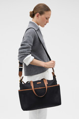 Profile view of model wearing the Oroton Lilly Nylon Baby Bag in Black/Cognac and Nylon fabric material for Women .