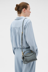Profile view of model wearing the Oroton Mica Texture Mini Bowler in Soot and Premium embossed ostrich leather for Women .