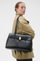 Profile view of model wearing the Oroton Etta Work Bag in Black and Premium epi leather for Women .