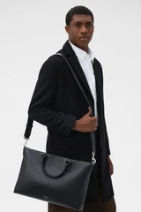 Profile view of model wearing the Oroton Paxton Briefcase in Black and Premium pebble leather for Men .