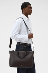 Profile view of model wearing the Oroton Paxton Briefcase in Dark Chocolate and Premium pebble leather for Men .