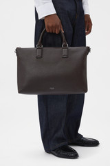 Profile view of model wearing the Oroton Paxton Briefcase in Dark Chocolate and Premium pebble leather for Men .