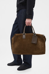 Profile view of model wearing the Oroton Paxton Suede Weekender in Husk Brown and Premium Grade A velvet-finish cow suede leather for Men .