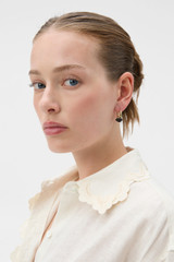 Profile view of model wearing the Oroton Penny Charm Hoops in Choc/Gold and Brass material for Women .