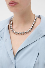 Profile view of model wearing the Oroton Penny Necklace in Silver and Brass material for Women .