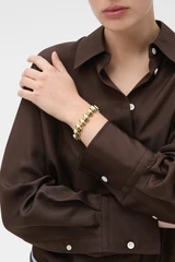 Profile view of model wearing the Oroton Penny Bracelet in Gold and Brass material for Women .