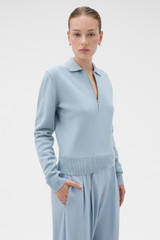 Profile view of model wearing the Oroton Long Sleeve Zip Polo in Twilight Blue and 100% mid-gauge merino wool fabric for Women .