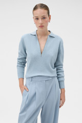 Profile view of model wearing the Oroton Long Sleeve Zip Polo in Twilight Blue and 100% mid-gauge merino wool fabric for Women .