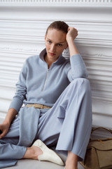 Profile view of model wearing the Oroton Long Sleeve Zip Polo in Twilight Blue and 100% mid-gauge merino wool fabric for Women .