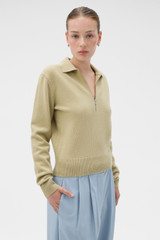 Profile view of model wearing the Oroton Long Sleeve Zip Polo in Haystack and 100% mid-gauge merino wool fabric for Women .
