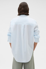 Profile view of model wearing the Oroton Washed Pleated Shirt in Soft Blue and 100% soft cotton fabric for Women .