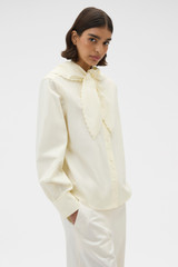 Profile view of model wearing the Oroton Scallop Tie Neck Shirt in Whipped Cream and 100% soft cotton fabric for Women .