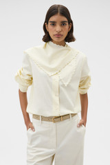 Profile view of model wearing the Oroton Scallop Tie Neck Shirt in Whipped Cream and 100% soft cotton fabric for Women .