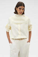 Profile view of model wearing the Oroton Scallop Tie Neck Shirt in Whipped Cream and 100% soft cotton fabric for Women .